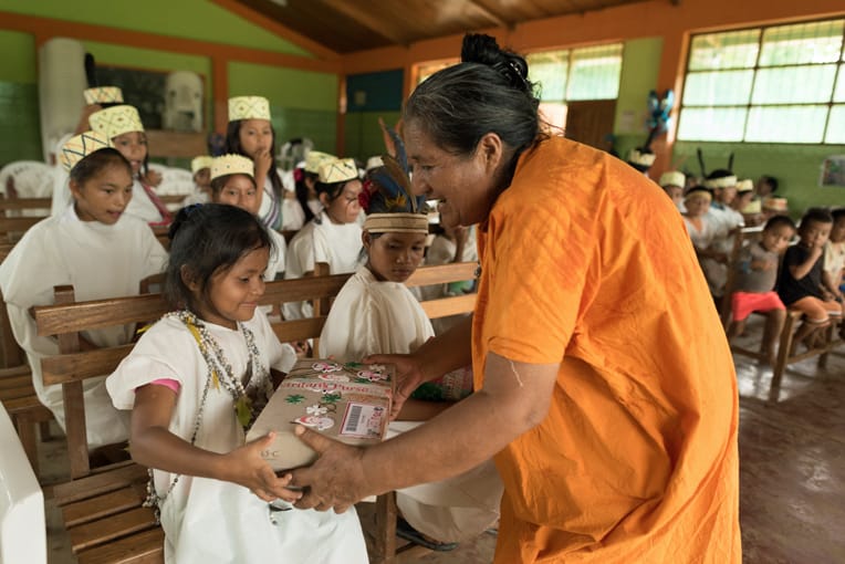 Raquel distributes shoeboxes in a river community.