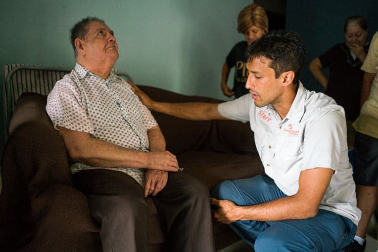 Andres Morales prays with Eugenio Rodriguez who received a generator from Samaritan’s Purse.