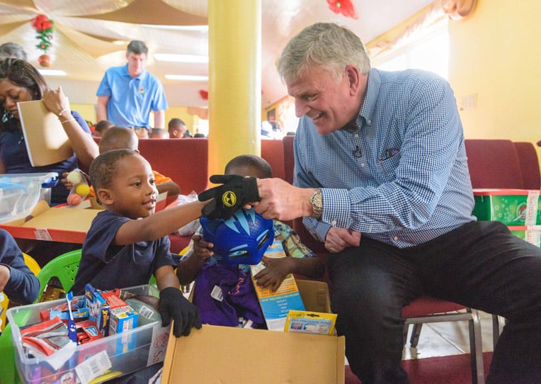 Franklin Graham helps a young boy with his shoebox gifts.