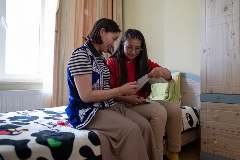 Dariya shows her mother, Saraa (left), her prayer journal and Bible from The Greatest Journey.