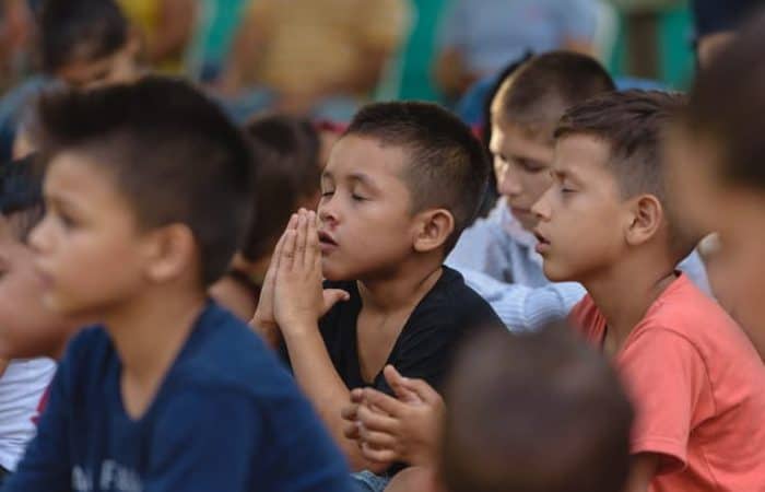 Children pray during the distribution. Will you keep these shoebox recipients in your prayers?