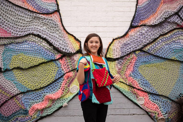 An artist at heart, Alathia displays an array of purses that she and her friends have made against the backdrop of a Fort Worth artist’s depiction of a butterfly.