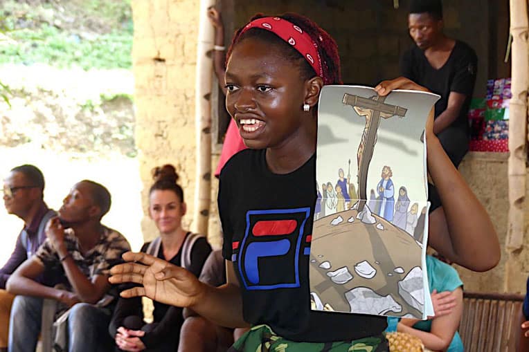 A student shares the Gospel with the boys and girls of Bolo using the Ministry Partner Guide.