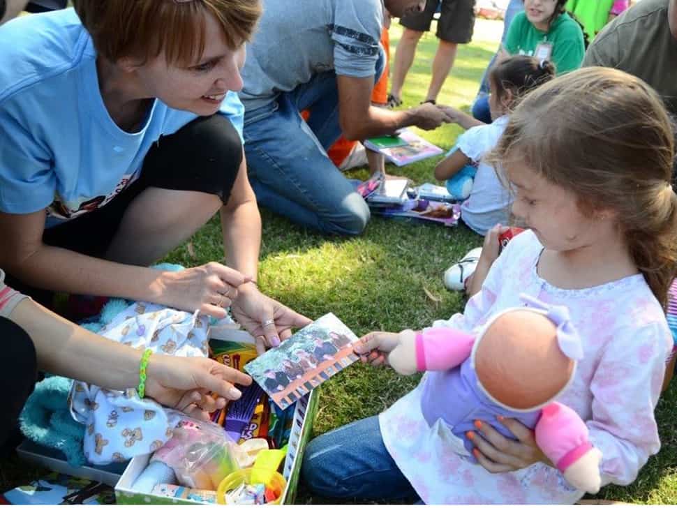 Frieda handing a young girl, Katalina from Uruguay her Operation Christmas Child Shoebox in 2015. (Photo credit: Frieda Wiebe) 