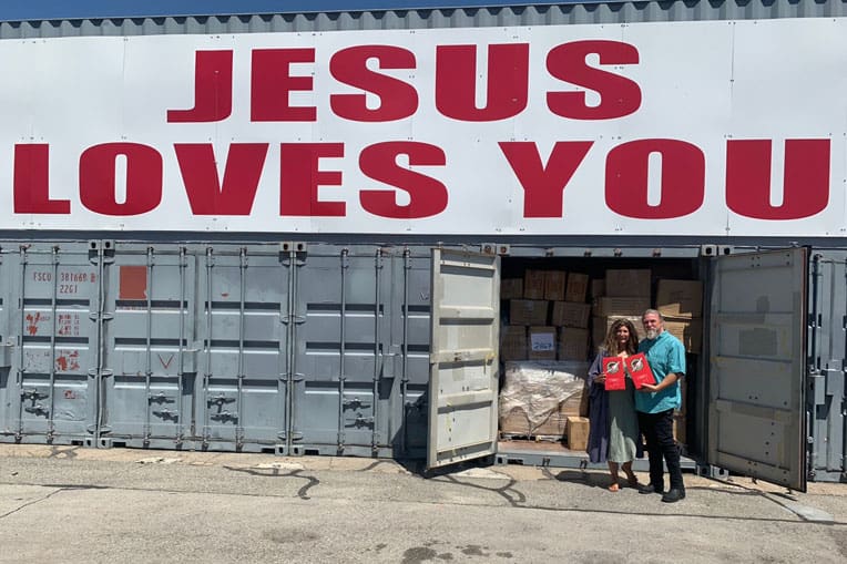 Alison Long and her husband, Terry, in front of a shipping container full of Operation Christmas Child items.