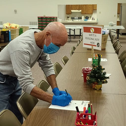 Families at Milan Baptist Church write notes to include in their shoebox gifts to delight the heart of the children who receive them. This station will be disinfected after each use to make it sanitary for the next family who visits to pack shoeboxes.