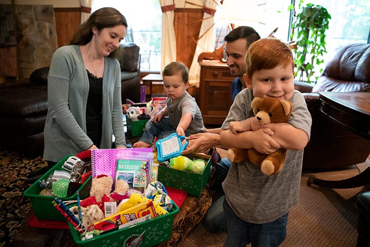 A young shoebox packer hugs a stuffed animal, a quality item that a shoebox recipient can cherish for many years.