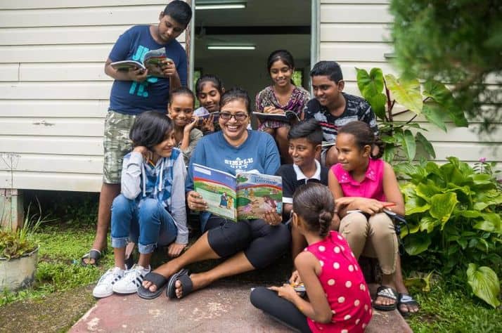 Children gather around Ravina Kumar to read some of the lessons in The Greatest Journey discipleship workbook.