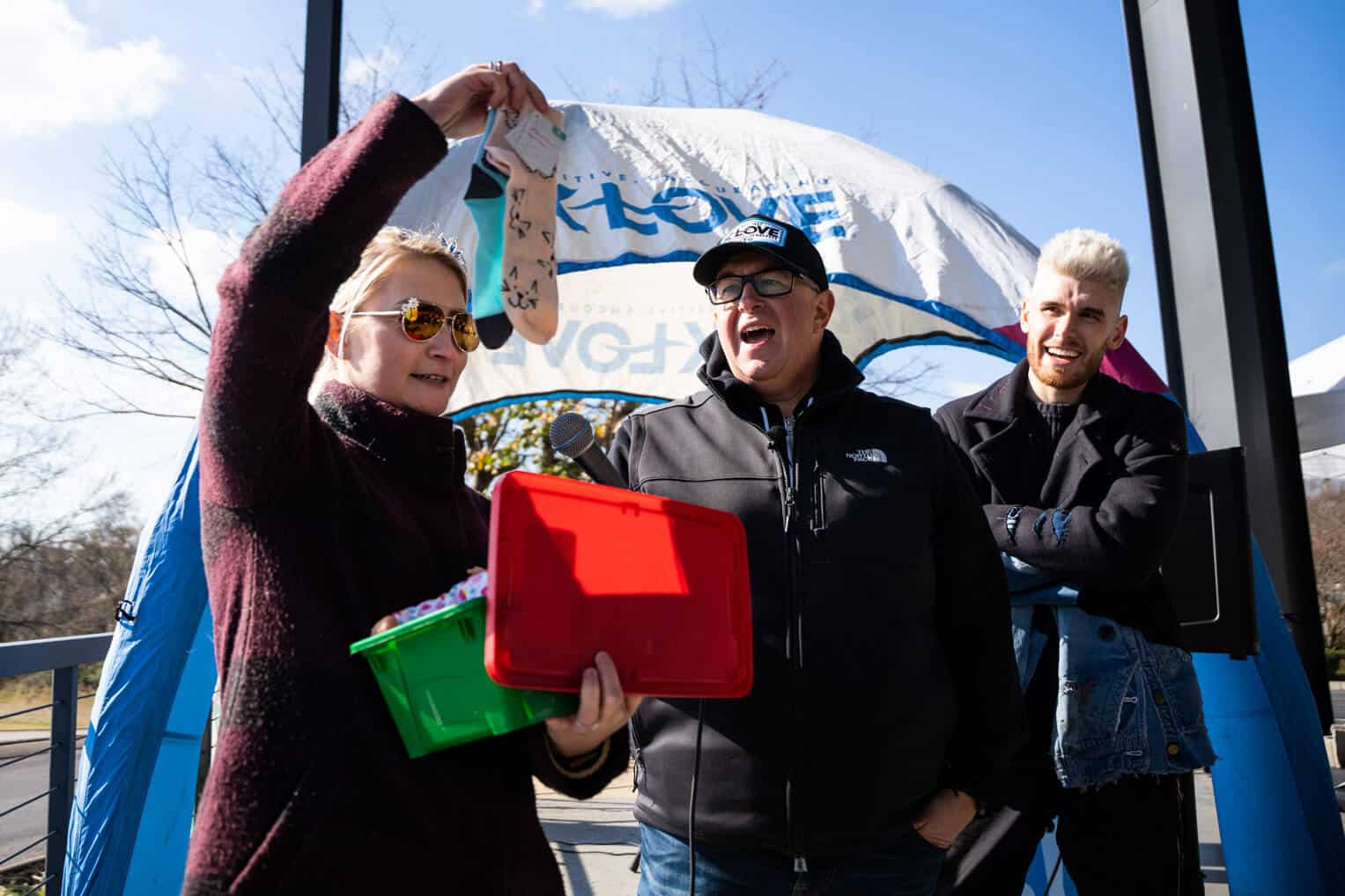 Elizabeth Groff adds socks to the 200 millionth shoebox gift in Franklin, Tennessee. She's joined by K-LOVE DJ Scott Smith and musician Colton Dixon.