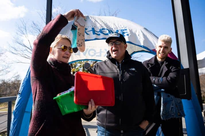 Elizabeth Groff adds socks to the 200 millionth shoebox gift in Franklin, Tennessee. She's joined by K-LOVE DJ Scott Smith and musician Colton Dixon.