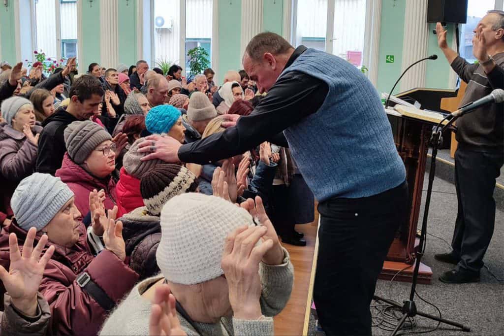 Pastor Ivan prays from the podium for members of his congregation.