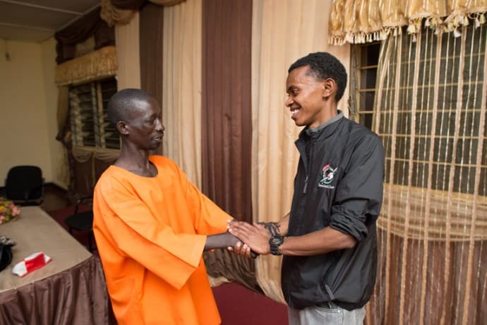 Alex shakes hands with the man who killed his uncle, Niyoneza Anastase, in Nyarugenge Prison in Kigali, Rwanda.