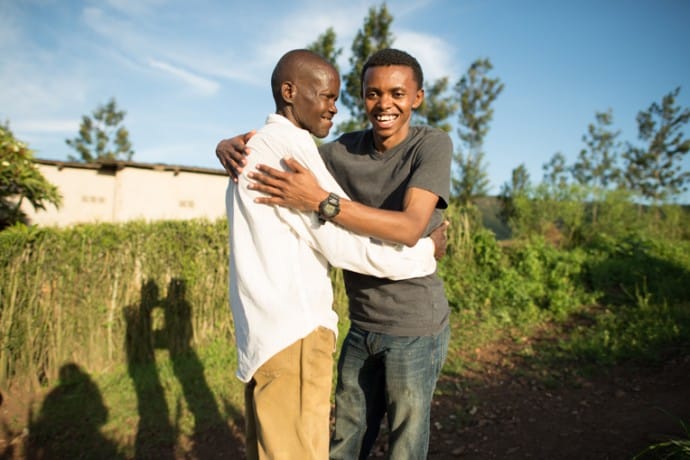 Alex and his remaining uncle, Rusanganwa, embrace next to a garden planted on the land where their house used to stand in Butamwa, Rwanda.