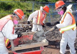 Three Samaritan's Purse volunteers dig through ash