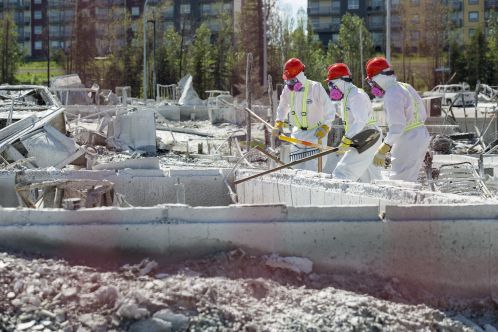 Volunteers in Tyvek suits sift through ashes