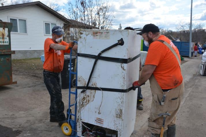 Samaritan’s Purse volunteers move a fridge filled with rotting food out of a Fort McMurray house to the curb for pickup.