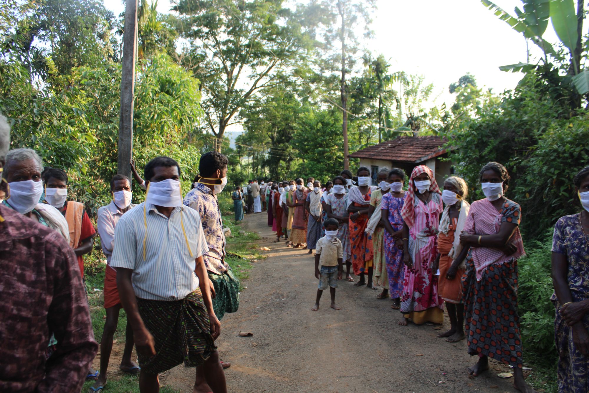 People stand in long lines to collect handouts of basic food items.