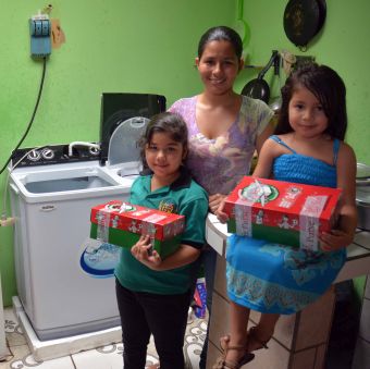 Yency and her two daughters who are holding shoeboxes