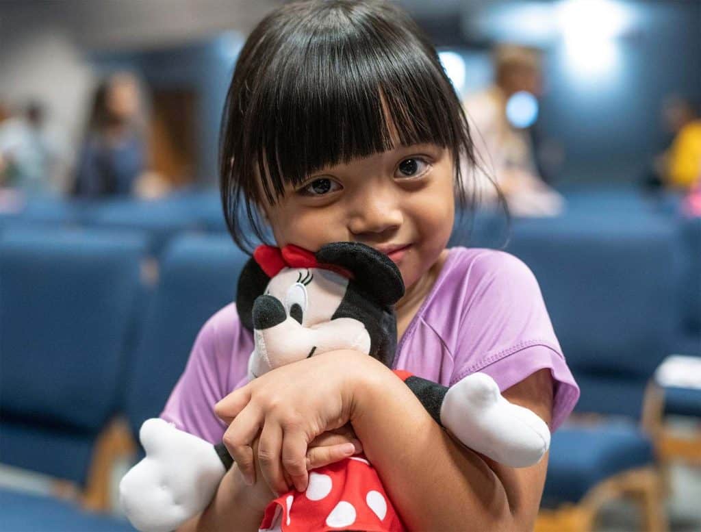 A girl hugs a favorite toy she received in her shoebox.