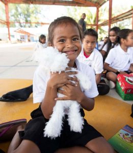 A student at Peleliu Elementary School in Palau hugs a favorite shoebox gift. The festive outreach event was the first ever in Palau.